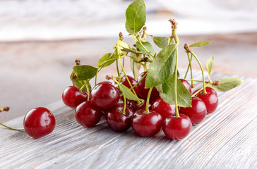 Fresh sweet cherries bowl with leaves on stone background, top view