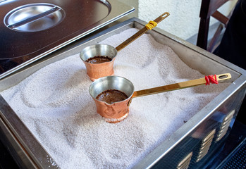 Hot tasty Coffee from copper cezve prepared on hot sand. Cezve to kitchen