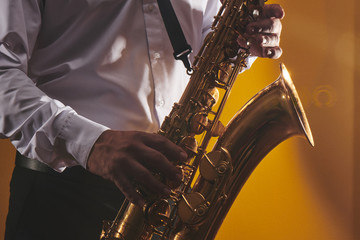 Portrait of professional musician saxophonist man in  white shirt plays jazz music on saxophone,...