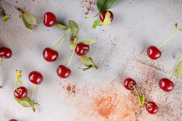 Fresh sweet cherries bowl with leaves on stone background, top view