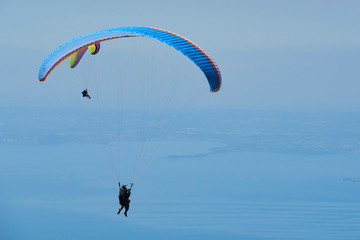 Paraglider flying over the Garda Lake (Lago di Garda or Lago Benaco), Panorama of the gorgeous Garda lake surrounded by mountains. Paragliding is very popular sport in Monte Baldo. Malcesine, Italy