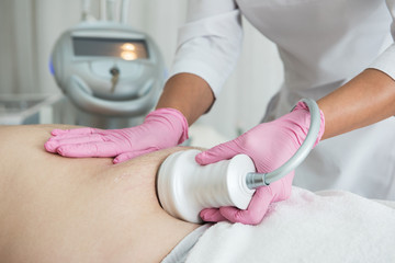 Closeup photo of fat man with big belly having cavitation procedure removing cellulite on abdomen in modern beauty clinic
