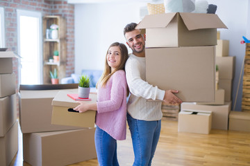 Young beautiful couple in love moving to new home, holding cardboard boxes very happy and cheerful for new apartment