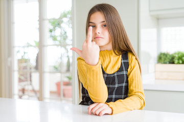 Young beautiful blonde kid girl wearing casual yellow sweater at home Showing middle finger,...