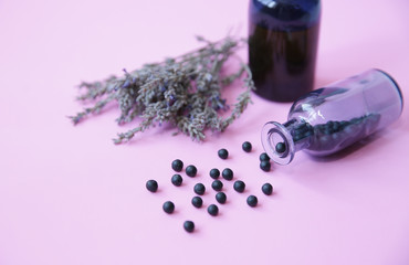 Homeopathic balls in a glass bottle and essential oil in a bottle and lavender herb on a pink background. Alternative medicine Herbal homeopathy Healthcare  Aromatherapy Close-up With copy space