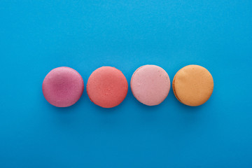 top view of colorful delicious French macaroons on blue bright background