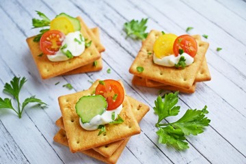 Delicious crackers with cheese sauce and vegetables.Snack on wooden background.