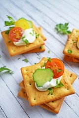 Delicious crackers with cheese sauce and vegetables.Snack on wooden background.
