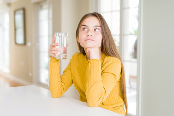 Beautiful young girl kid drinking a fresh glass of water serious face thinking about question, very...