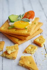 Delicious crackers with cheese sauce and vegetables.Snack on wooden background.