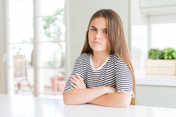 Beautiful young girl kid wearing stripes t-shirt skeptic and nervous, disapproving expression on face with crossed arms. Negative person.