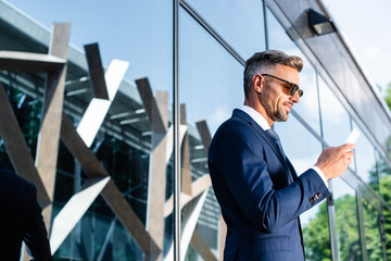 side view of handsome man in suit and glasses using smartphone