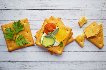Delicious crackers with cheese sauce and vegetables.Snack on wooden background.