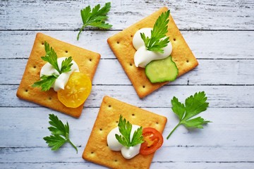 Delicious crackers with cheese sauce and vegetables.Snack on wooden background.