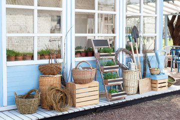 Harvest concept. Wicker baskets next to garden equipment by the wall of a blue country house. The decor of the courtyard of a country house. Gardening concept. Autumn harvest of plenty. 