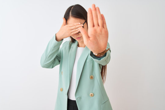 Chinese businesswoman wearing elegant jacket and glasses over isolated white background covering eyes with hands and doing stop gesture with sad and fear expression. Embarrassed and negative concept.