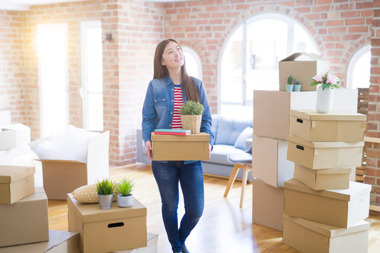 Beautiful asian young woman holding boxes, smiling happy moving to a new home