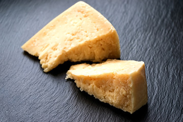 Parmesan cheese on black stone background. Top view, copy space.