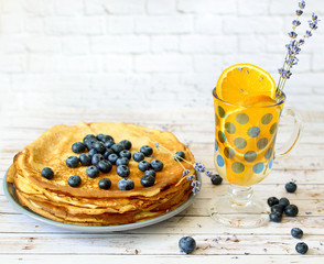 Pancakes with blueberries leaf on top and orange citrus lemonade with lavender sticks. Thin damn...