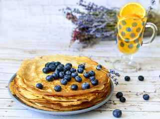 Pancakes with blueberries leaf on top and orange citrus lemonade with lavender sticks. Thin damn pancakes. Morning breakfast. diet. Russian bliny