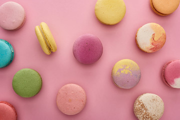 Fototapeta premium pattern of multicolored tasty French macaroons scattered on pink background