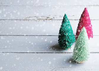 Bottle brush Christmas trees in bright colors on wood background with copy space.