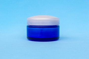 Blank blue cream jar on light background. Cosmetic skincare products, modern concept of organic beauty trend.