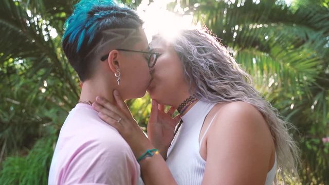 Modern urban homosexual couple. Blue hairstyle and delicate tender kiss. Love is love. Romantic kiss between young girlfriends. Love last forever. Proud to be gay.