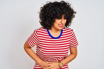 Young arab woman with curly hair wearing striped t-shirt over isolated white background with hand on stomach because nausea, painful disease feeling unwell. Ache concept.