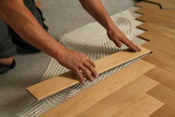 Worker laying parquet flooring. Worker installing wooden laminate flooring