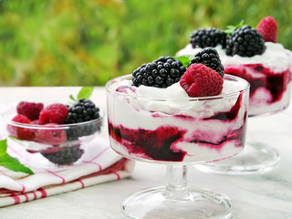 Berry fruit fool dessert in glass bowl. Sweetened and pureed blackberries folded into whipped cream topped with whole blackberries and raspberries.