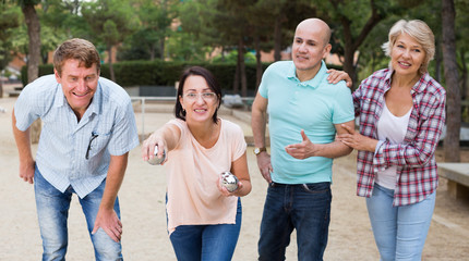 Cheerful males and females playing petanque