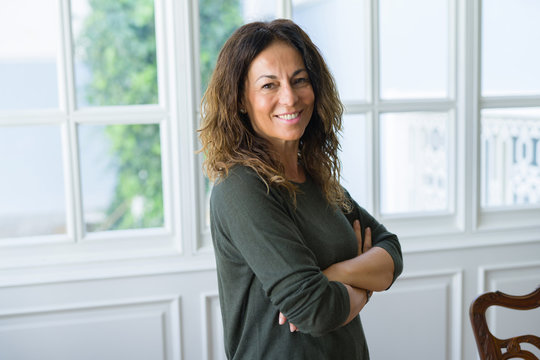 Beautiful middle age woman at home smiling cheerful with arms crossed