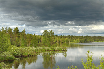 Dark cloud over northern forest lake in Finnish Lapland. Kuusamo