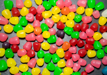 Multicolored gummy fruit in a black background.