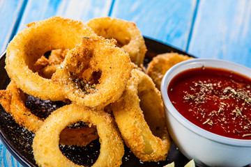 Onion rings with sauce on wooden table