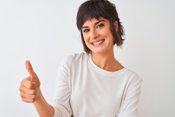 Young beautiful woman wearing casual t-shirt standing over isolated white background happy with big smile doing ok sign, thumb up with fingers, excellent sign