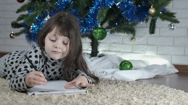 List of presents for Christmas. Little girl makes a list of gifts for the new year and christmas.