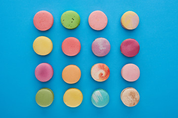flat lay with multicolored tasty French macaroons on blue bright background