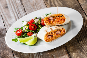 Burrito with vegetable salad on white plate