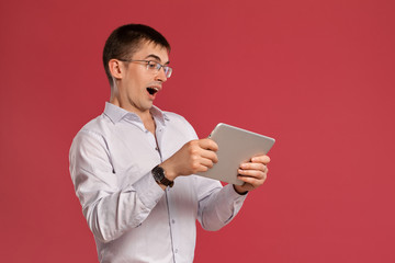 Young man in a classic white shirt is posing over a pink background.