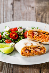 Burrito with vegetable salad on white plate