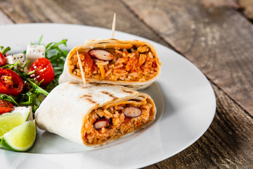 Burrito with vegetable salad on white plate