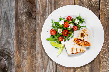 Burrito with vegetable salad on white plate