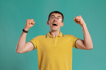 Fototapeta premium Handsome guy in a yellow casual t-shirt is posing over a blue background.