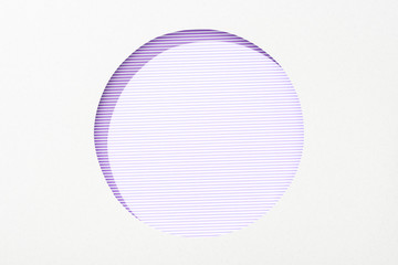 cut out round hole in white paper on violet and white striped background