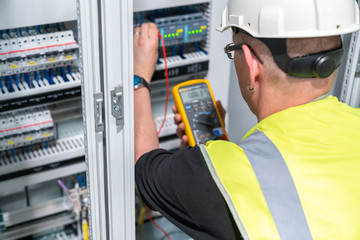 an electrical engineer performs a measurement in a control cabinet