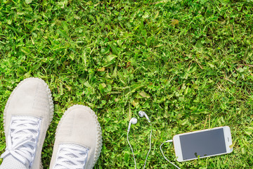 Sneakers on the green grass with a mobile phone and headphones