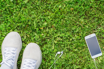 Sneakers on the green grass with a mobile phone and headphones