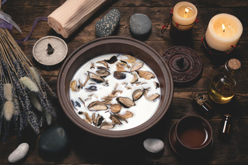 Aromatherapy concept background. Milk in a bowl with incense and essential oil on a brown wooden table background.